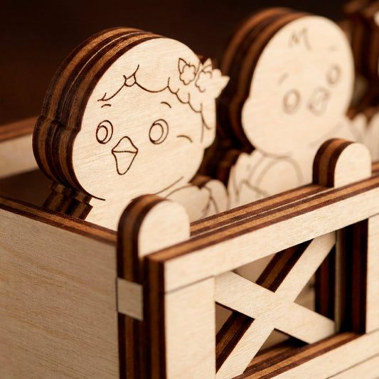 Wooden laser cut toy figures of a girl and a boy in a wooden crib