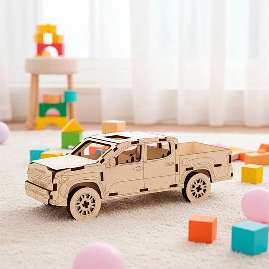 Laser cut plywood wooden 3D model kit of a modern pickup truck with four doors and an open bed, displayed on a soft white rug surrounded by colorful toy blocks in a bright indoor playroom setting