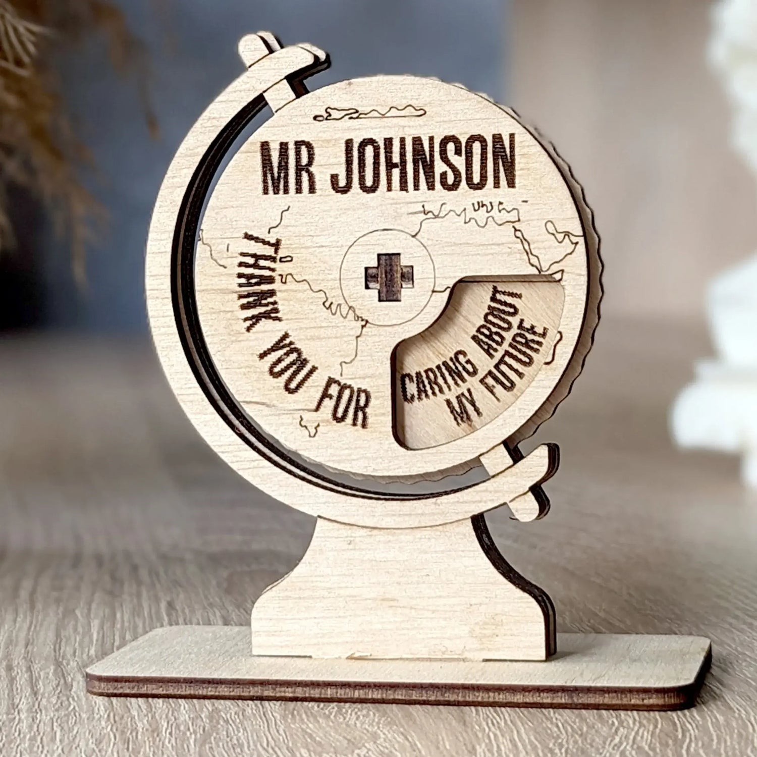 Personalized globe teacher gift made of laser cut plywood with engraved thank you message, standing on a desk