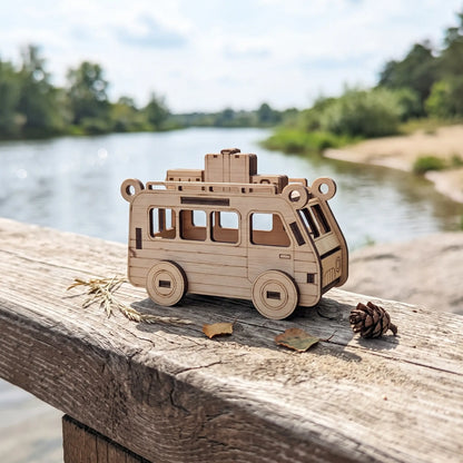 Natural laser cut plywood travel van figurine with roof luggage sitting on wooden bridge railing beside sunny river.