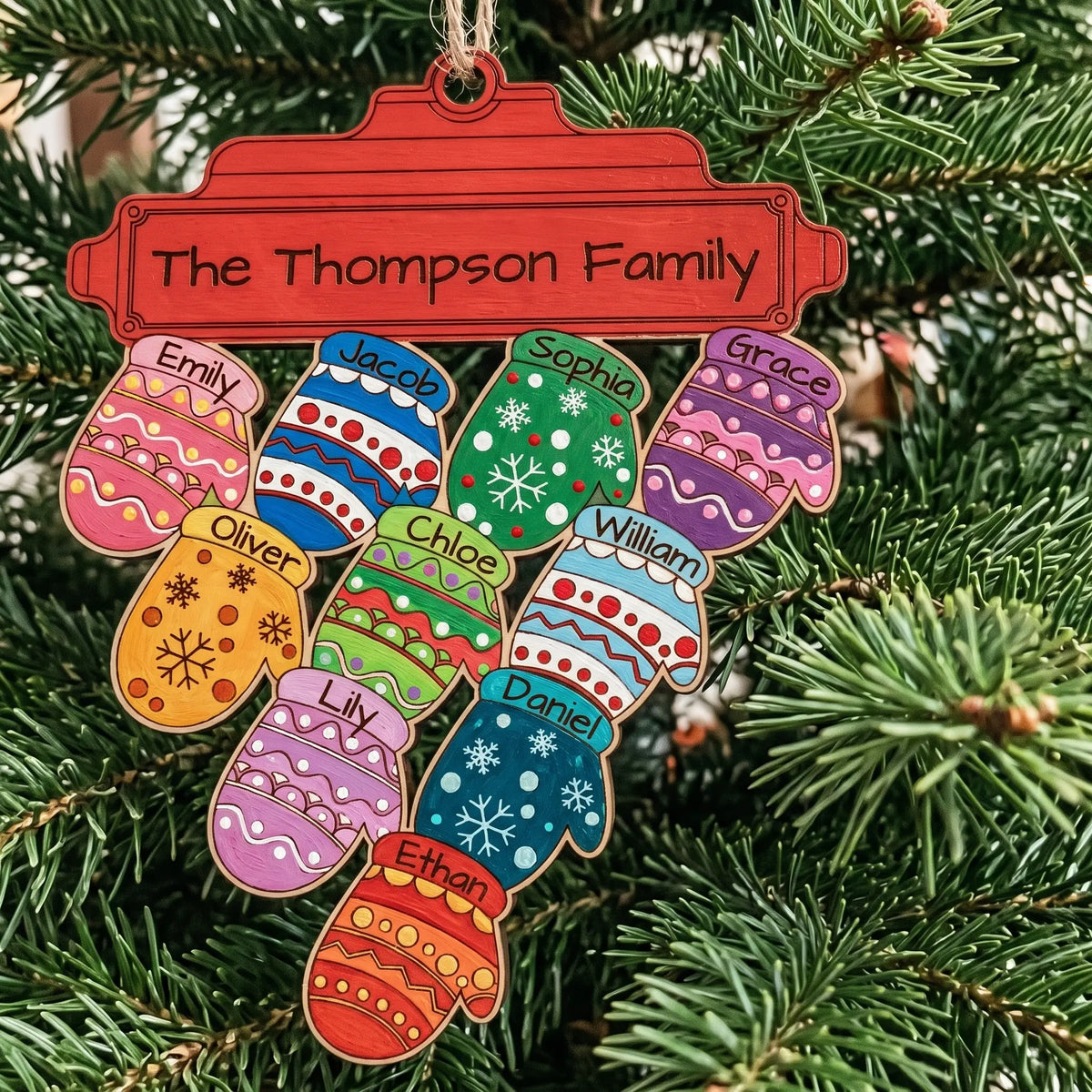 Painted laser cut plywood Christmas mitten family ornament with 10 colorful name mittens hanging on lush evergreen branches.