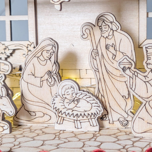 Close-up of baby Jesus in a wooden Nativity Scene, with Mary and Joseph standing nearby, engraved and cut from plywood. Designed as a layered laser cut digital template