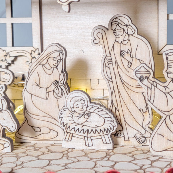 Close-up of baby Jesus in a wooden Nativity Scene, with Mary and Joseph standing nearby, engraved and cut from plywood. Designed as a layered laser cut digital template