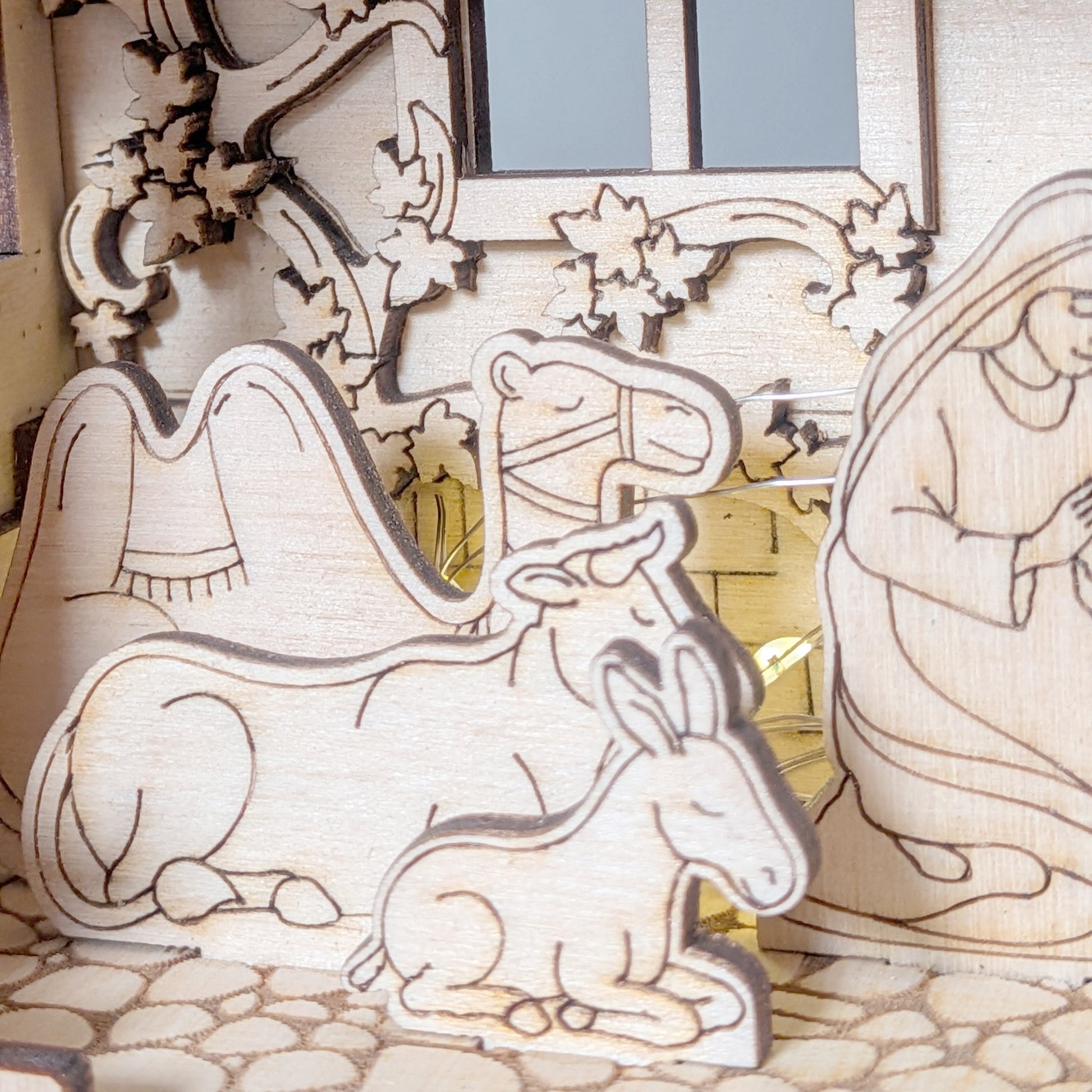 Close-up of wooden Nativity Scene animals including a camel, cow, and donkey, engraved and layered from plywood. Digital laser cut template for DIY Christmas decor