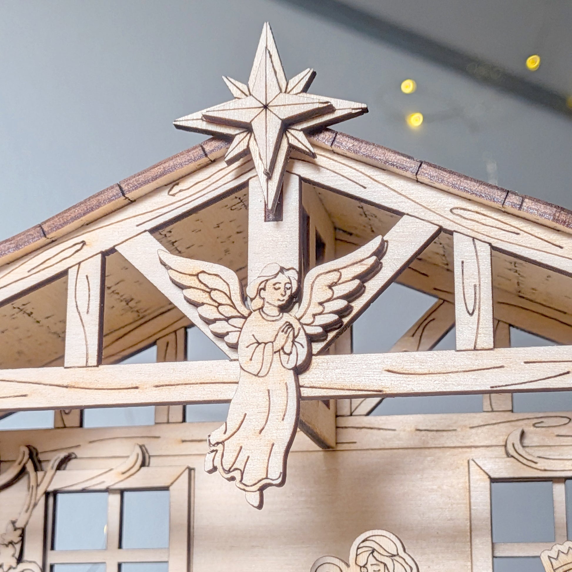 Close-up of wooden Nativity Scene laser cut angel and Bethlehem star detail on the stable roof. Christmas decoration made from a digital laser cut template file
