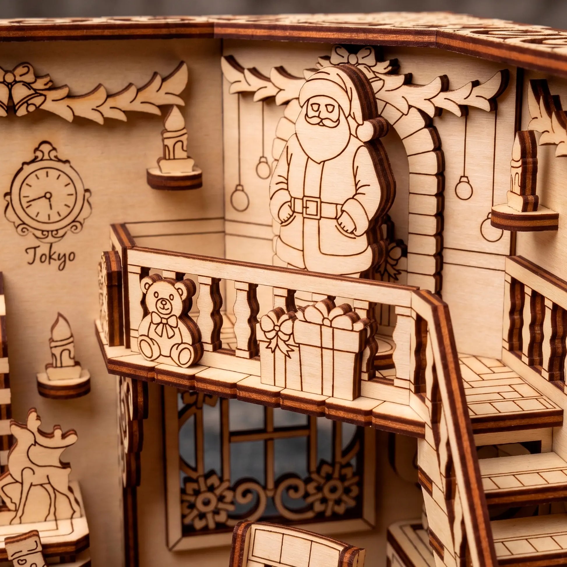 Close-up of a laser cut plywood Santa figurine on a balcony with gifts, reindeer decor, and dark charred edges.