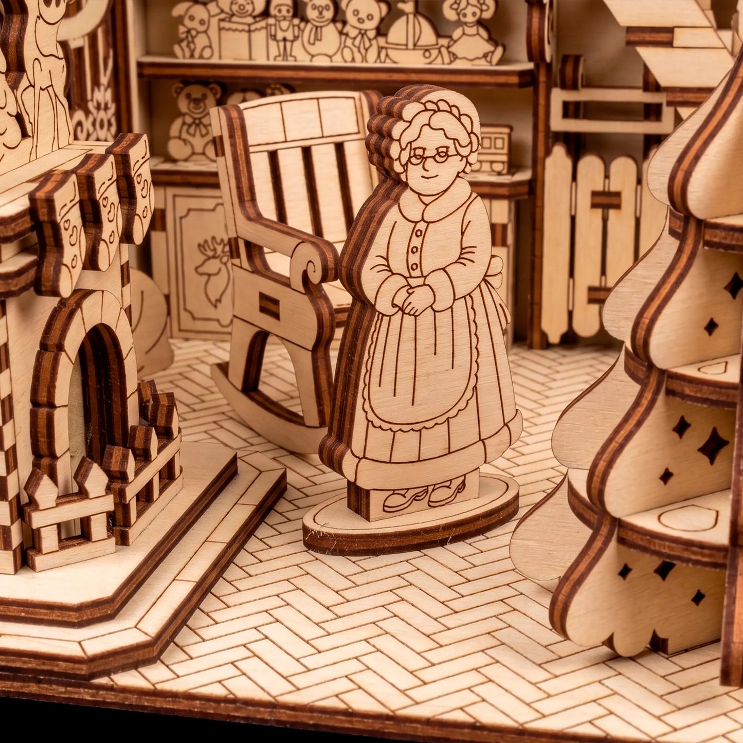 Detail of a laser cut plywood Mrs. Claus figurine standing on a herringbone floor near a rocking chair.
