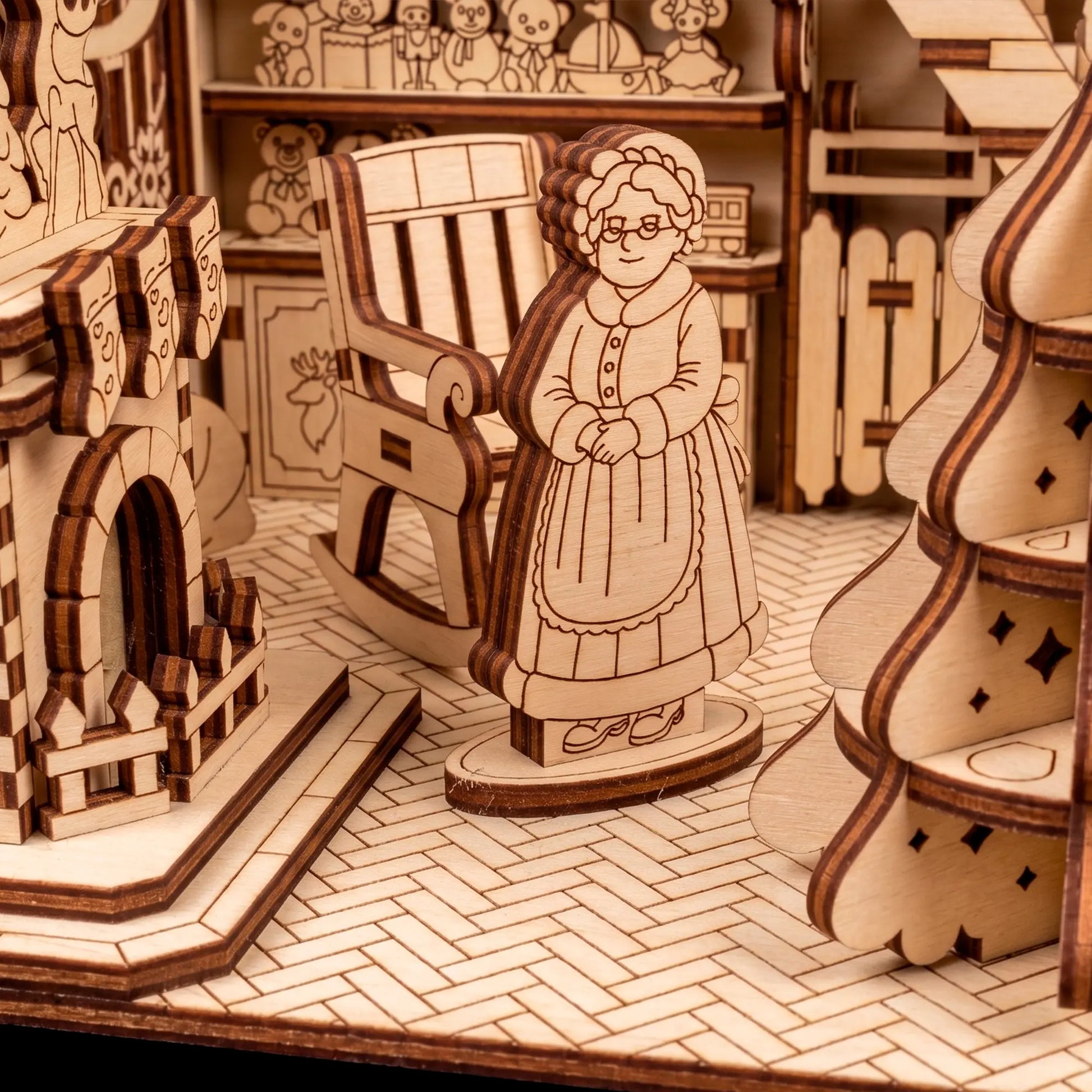 Detail of a laser cut plywood Mrs. Claus figurine standing on a herringbone floor near a rocking chair.