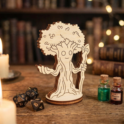 A single 3D forest mage tabletop miniature made from layered laser-cut wood. The character is a sentient tree-man holding a staff. Posed on a wooden desk next to metal polyhedral gaming dice and small glass bottles with red and green potion liquids.