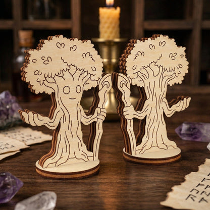 Two laser-cut plywood miniatures of a forest mage character, designed as a sentient tree with a friendly face and a staff. The wooden figurines are displayed on a dark surface alongside magical props like a lit candle, purple crystals, and runic papers for a mystical aesthetic.
