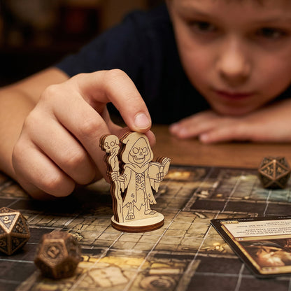 A Dark Necromancer tabletop miniature made from layered plywood, being used during a gaming session on a dungeon map. The shot shows the figurine in focus as a player interacts with it, surrounded by d20 dice and fantasy game cards.
