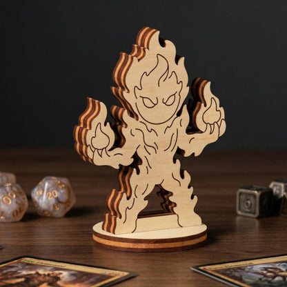 Detailed view of a laser cut plywood fire elemental figurine with engraved flames, standing on a table with RPG dice and cards.