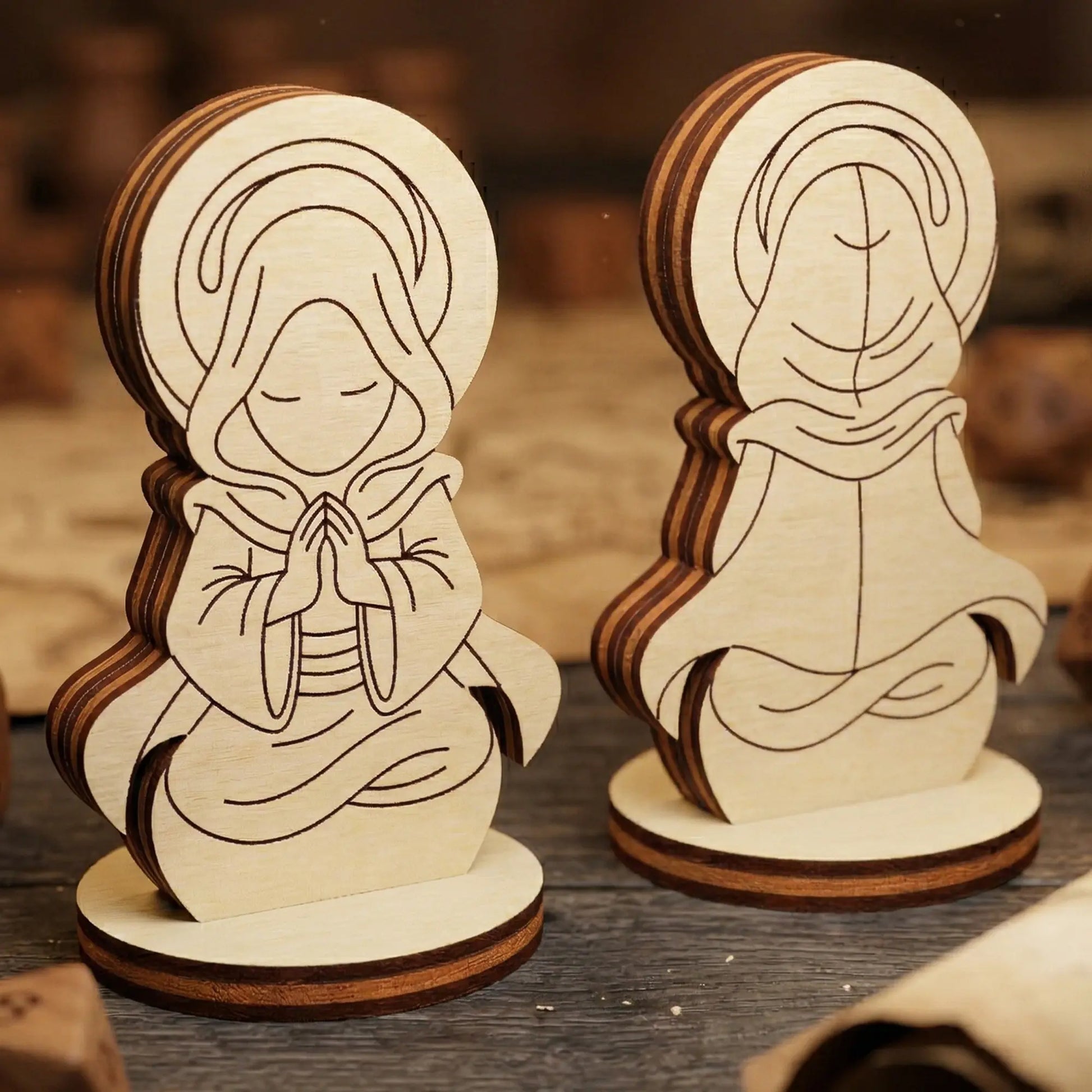 Front and back views of a praying holy monk made of laser cut plywood. Wood dice and a map scroll sit in the background.