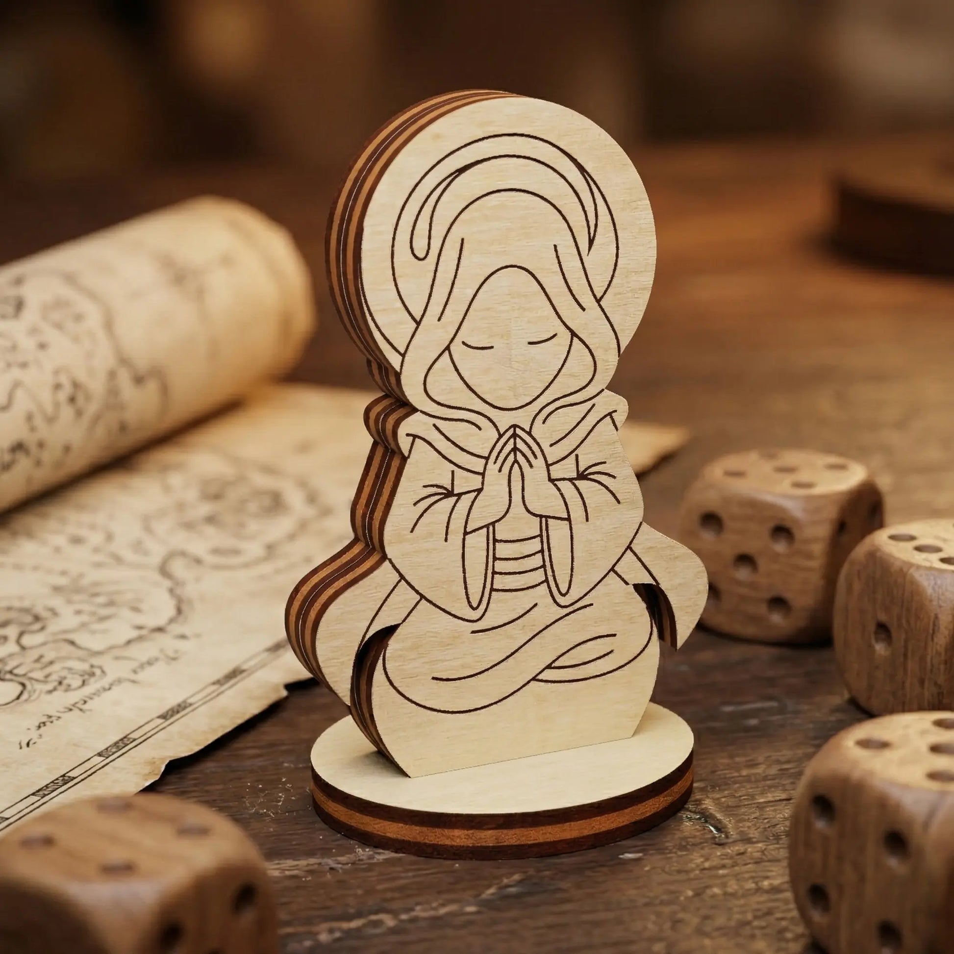 Close-up of a laser cut plywood holy monk figurine with detailed engravings of a hooded figure praying among wooden dice.
