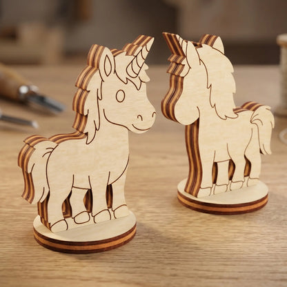 Front and back view of two magical unicorn figurines made of laser cut plywood, standing on a wooden surface in a workshop.
