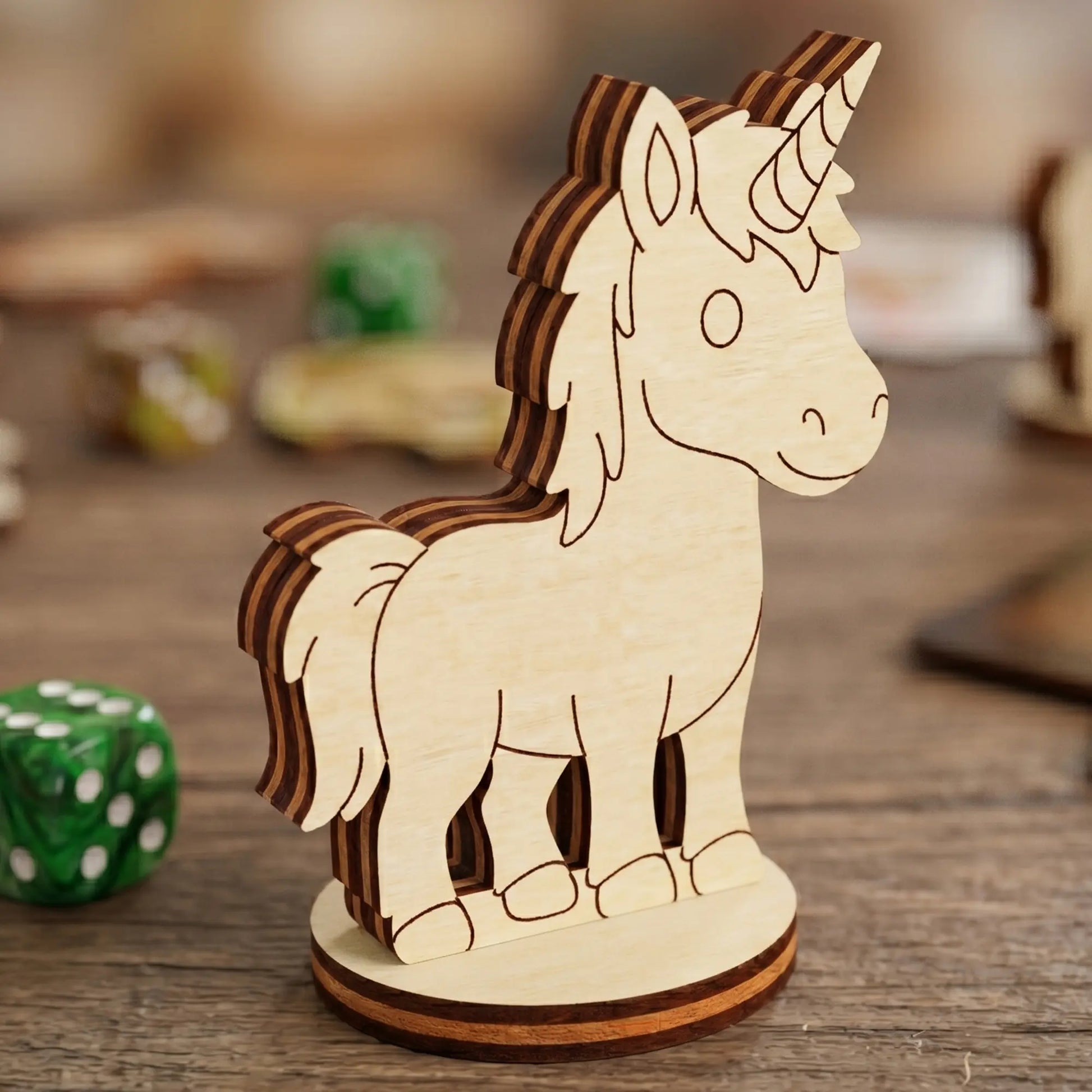 Close-up of a laser cut plywood unicorn figurine with engraved details and a spiraled horn, standing near a green gaming die.