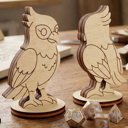 Front and back views of a falcon bird figurine in laser cut plywood, standing on a wooden table with pearl-colored RPG dice
