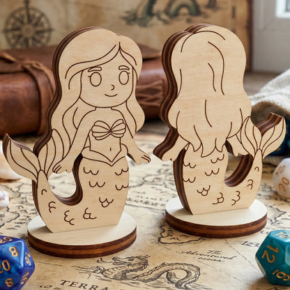 Front and back views of a laser cut plywood mermaid figurine on an old fantasy map with sea shells and blue d20 gaming dice.