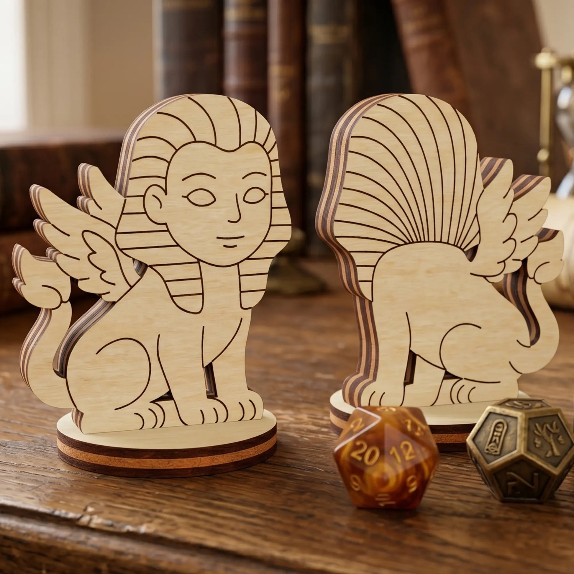 Front and back of a laser cut plywood sphinx figurine on a wooden table with vintage books and amber polyhedral dice.