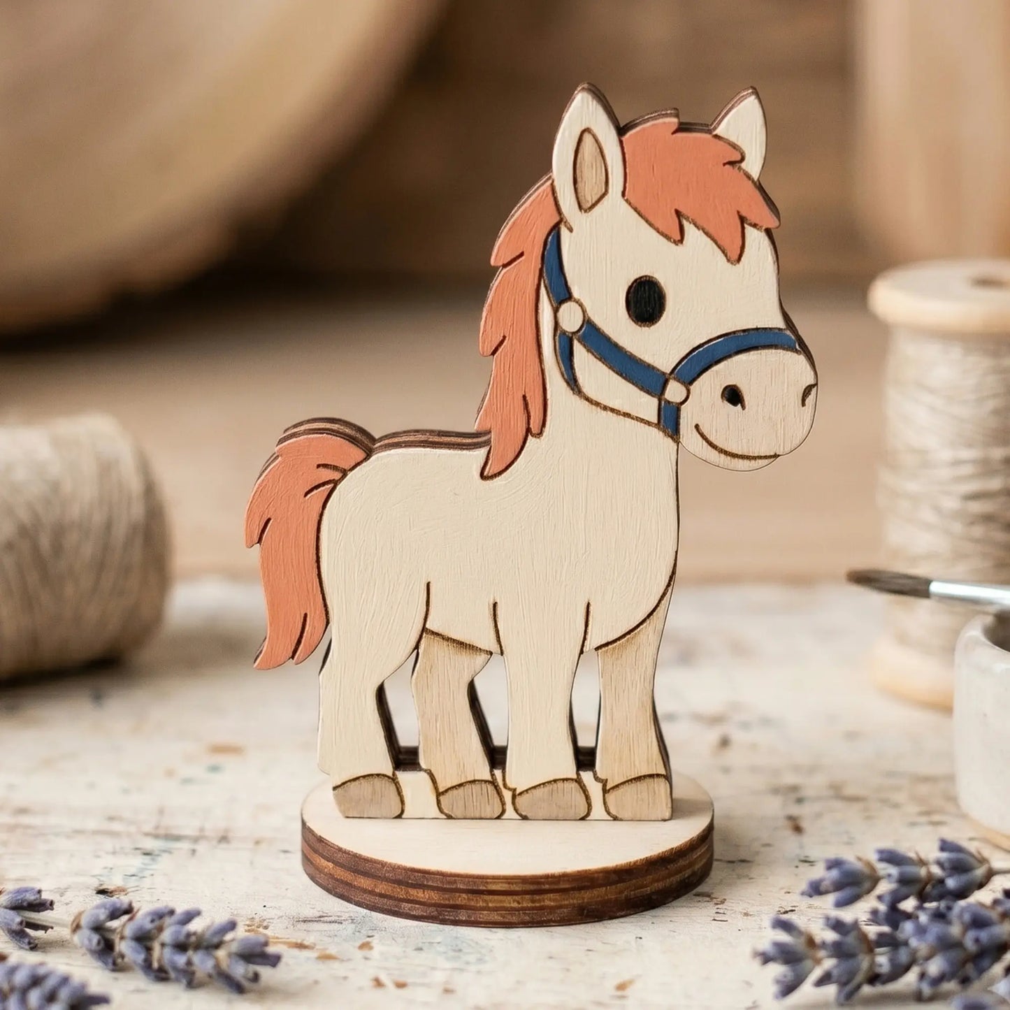 A painted miniature laser cut plywood horse craft token with a brown mane and blue halter, staged near dried lavender.