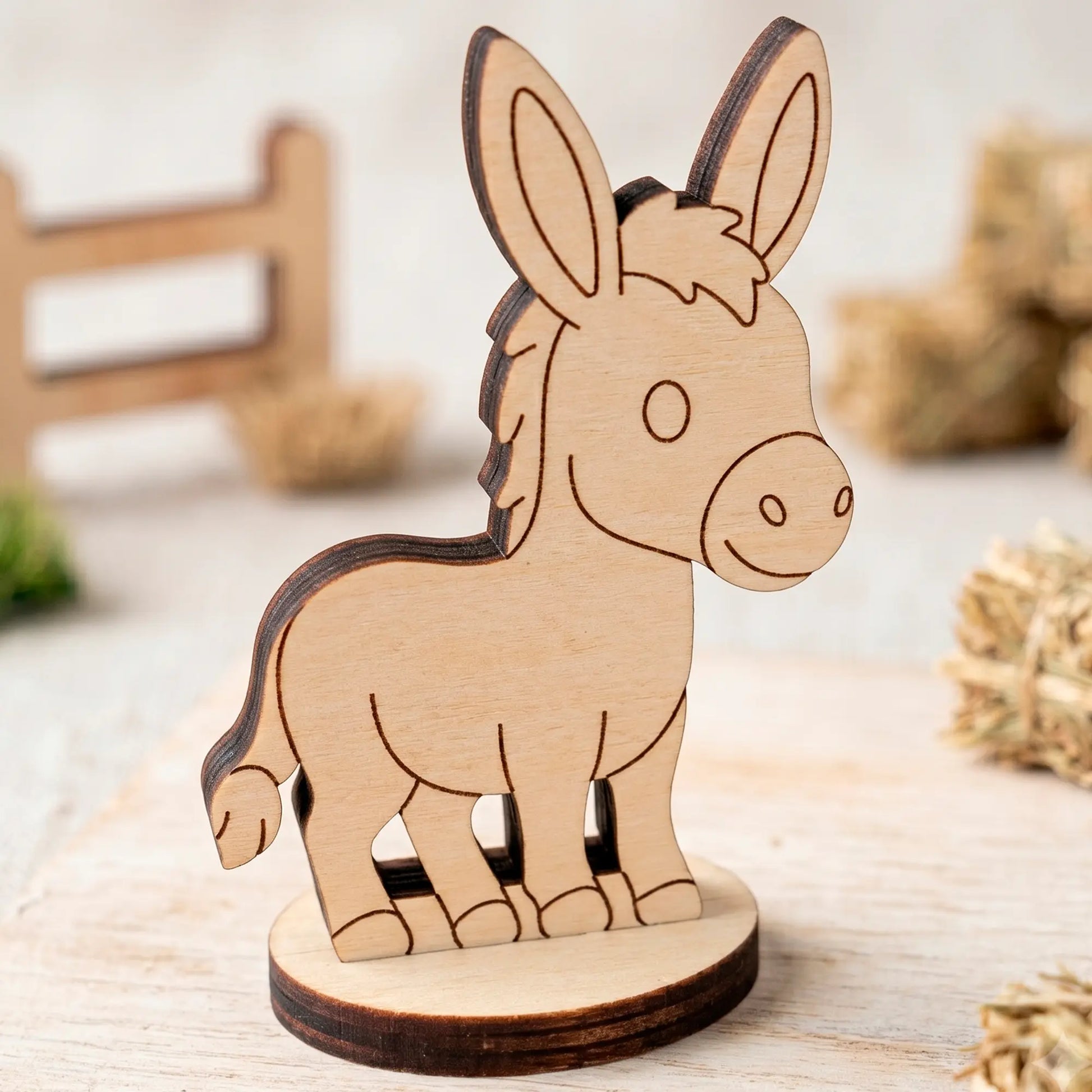 Close-up of an unpainted miniature laser cut plywood donkey figurine standing on a light wooden table surface.