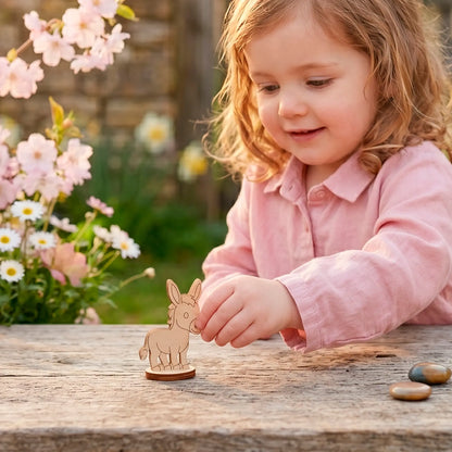 Miniature laser cut plywood donkey figurine on a picnic blanket near fruit, with a smiling child pointing at it