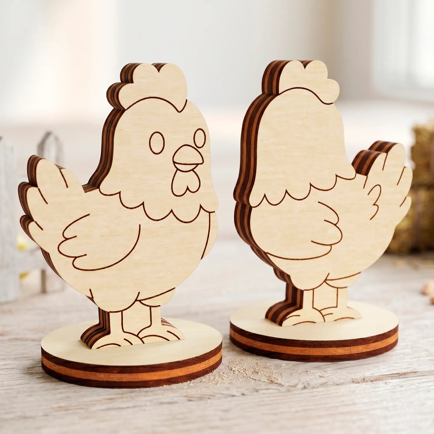 Two laser cut plywood cute hen figures with detailed burnt edges standing on a light rustic wooden surface