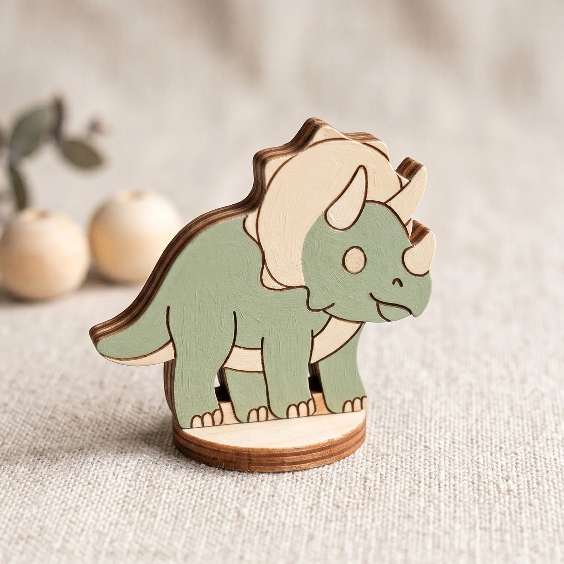 Single laser cut plywood triceratops figurine painted in a light green color, standing on a textured linen surface.