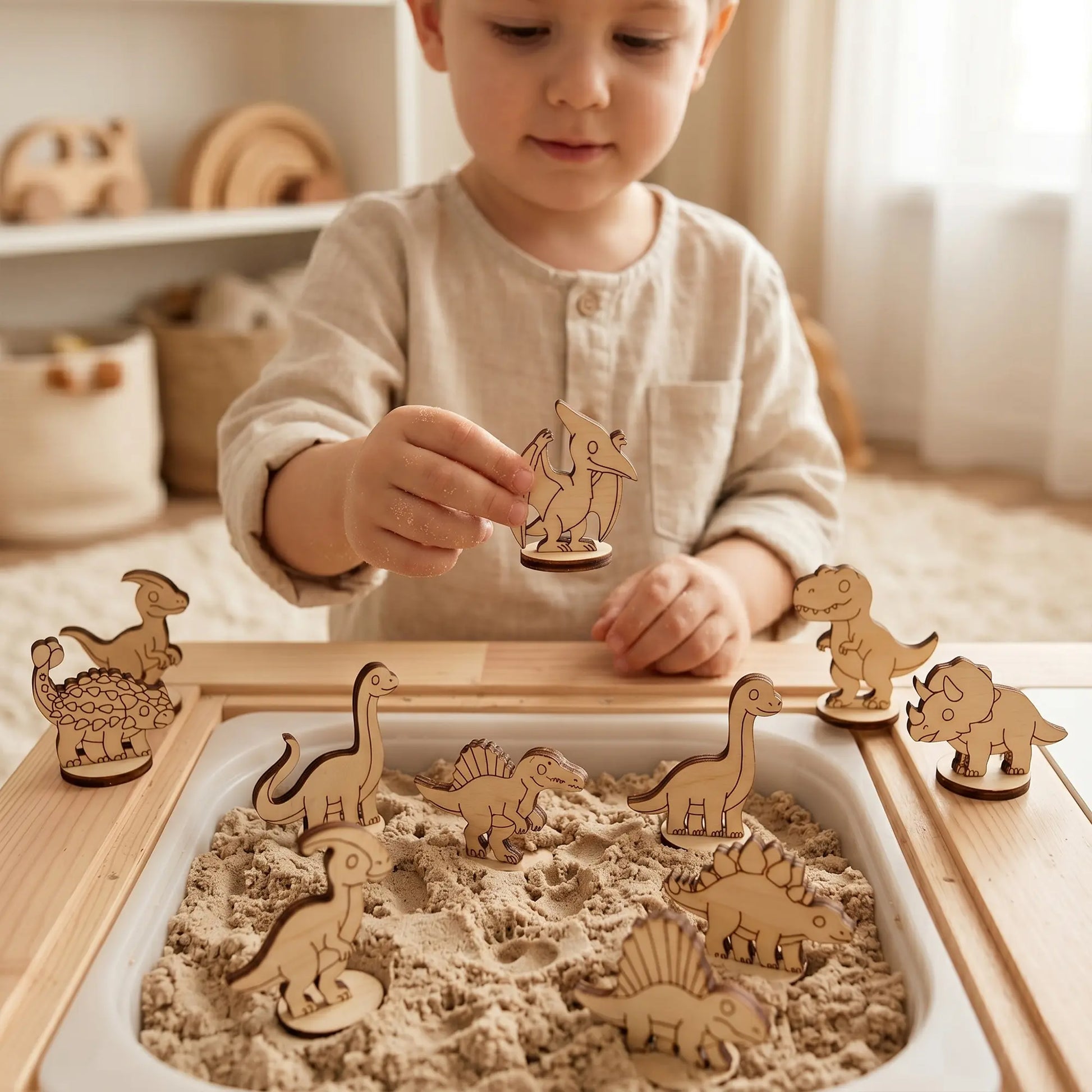 Child playing with a laser cut plywood pterodactyl toy over a sensory sand table filled with other wood dinosaurs.