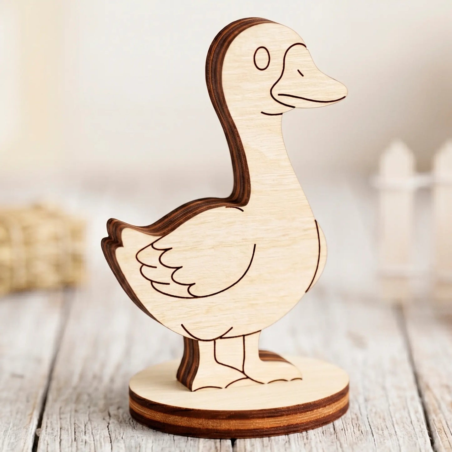 Profile view of a single laser cut plywood goose figurine on a round stand with a blurry white fence in the background.