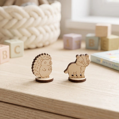 Close-up of laser cut plywood hedgehog and badger figurines on round bases standing beside pastel wooden toy blocks.