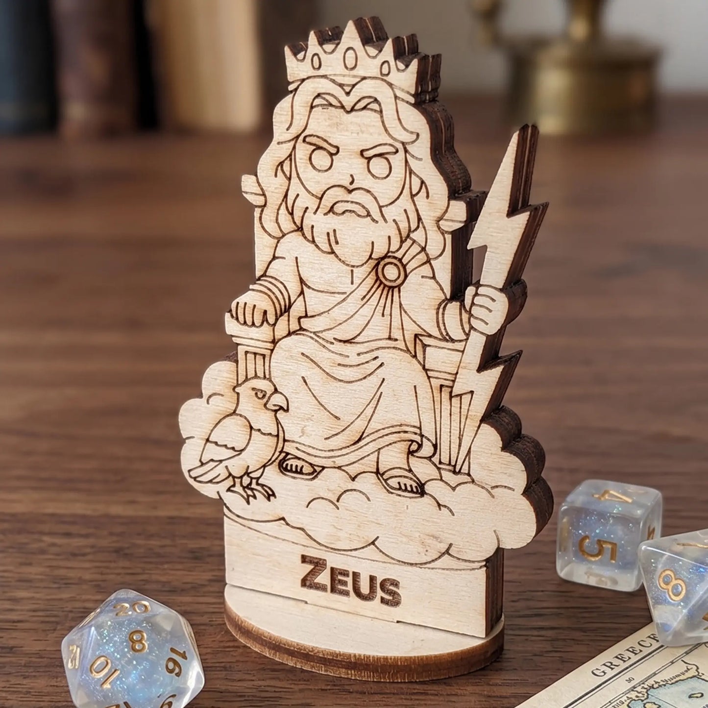 Laser cut plywood Zeus gaming miniature on a wooden table with sparkly d20 and d8 dice for tabletop RPG game scale