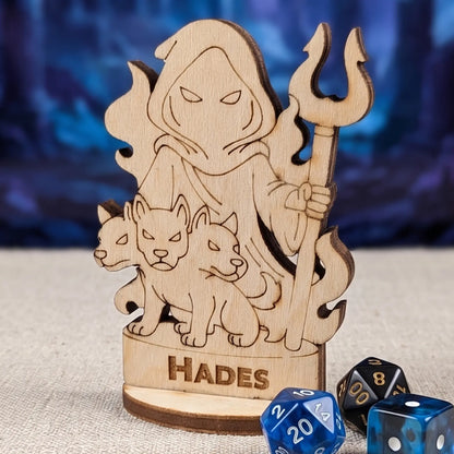 Macro shot of laser cut plywood Hades miniature on fabric with blue polyhedral RPG dice for tabletop gaming scale ref