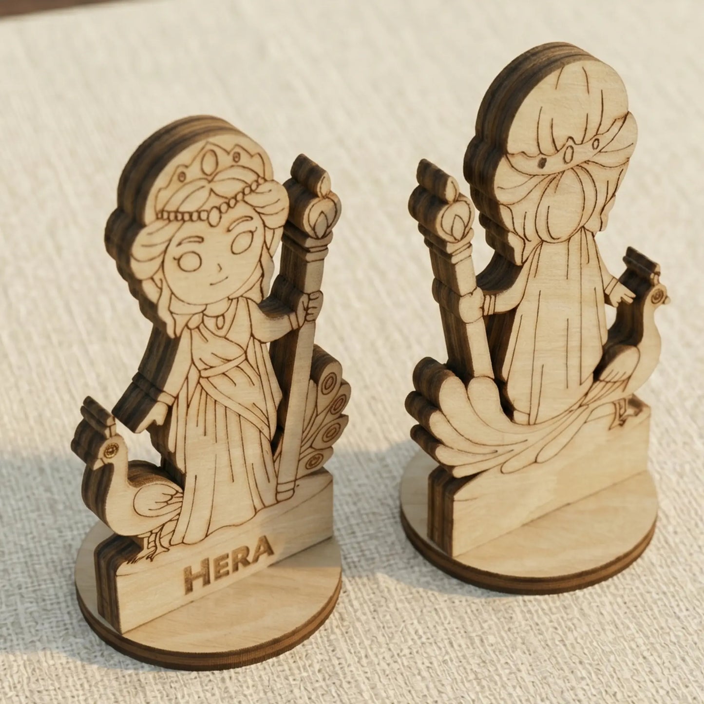 Angled side view of a laser cut plywood Hera figurine highlighting the dark brown burnt wood edges and peacock engravings.