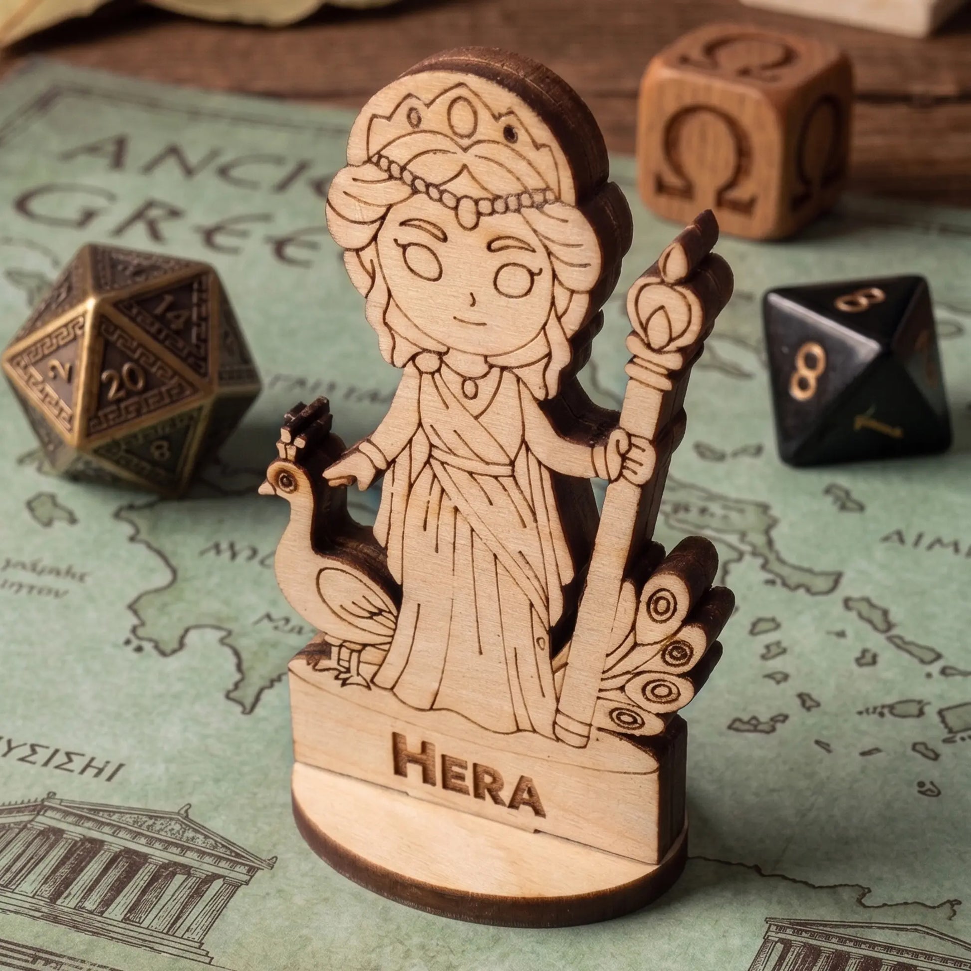 Laser cut plywood Hera tabletop gaming miniature on an ancient Greece map, surrounded by bronze and black metal RPG dice