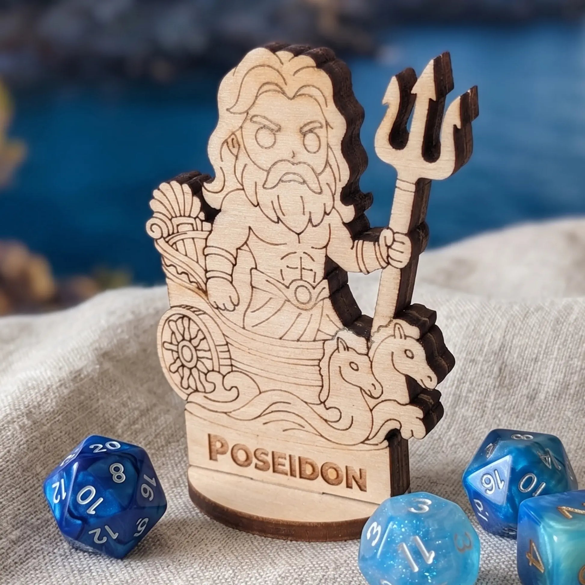 Macro shot of laser cut plywood Poseidon miniature on textured fabric with blue polyhedral dice for tabletop gaming scale