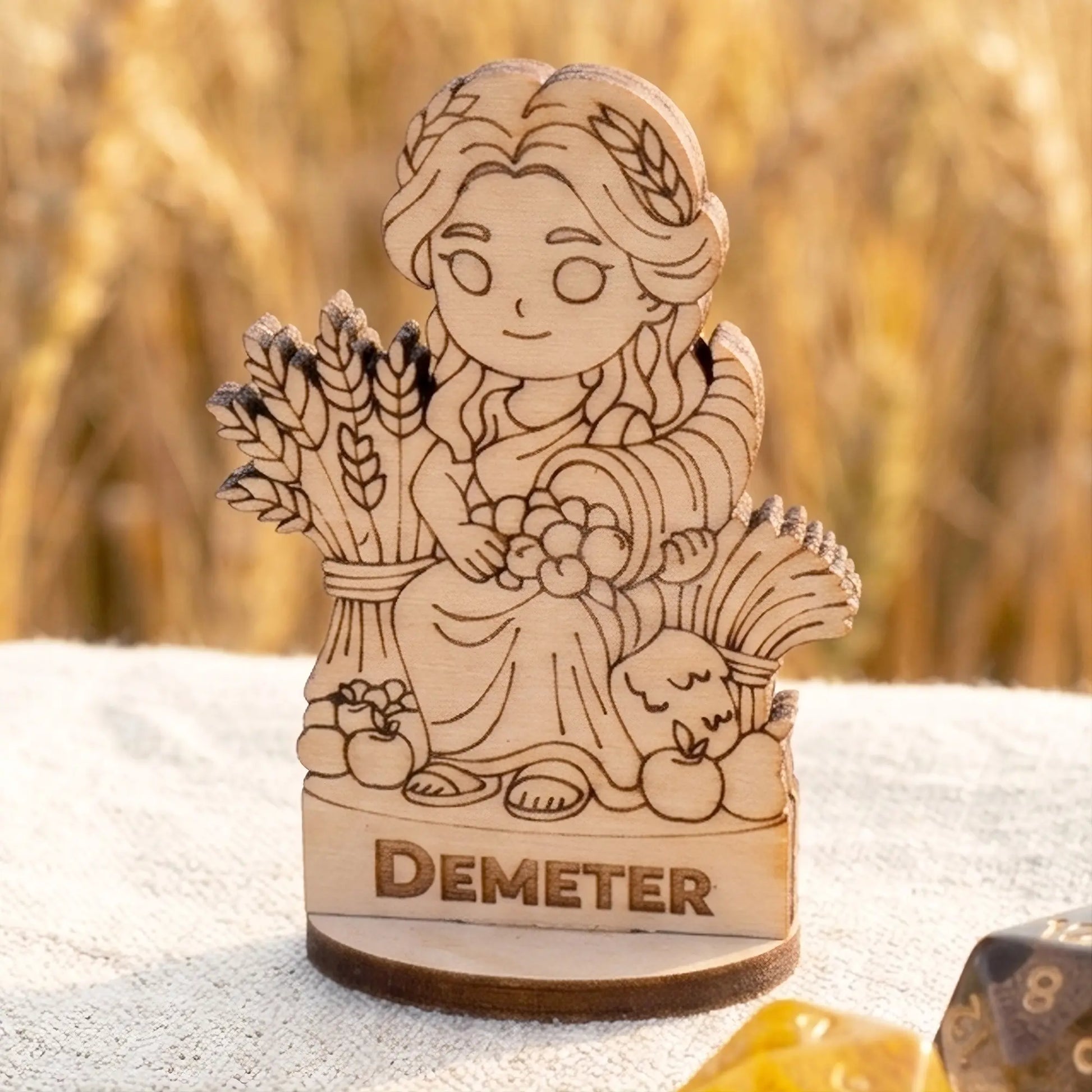 Detailed laser cut plywood Demeter gaming miniature with cornucopia and wheat stalks, showing natural wood grain and texture