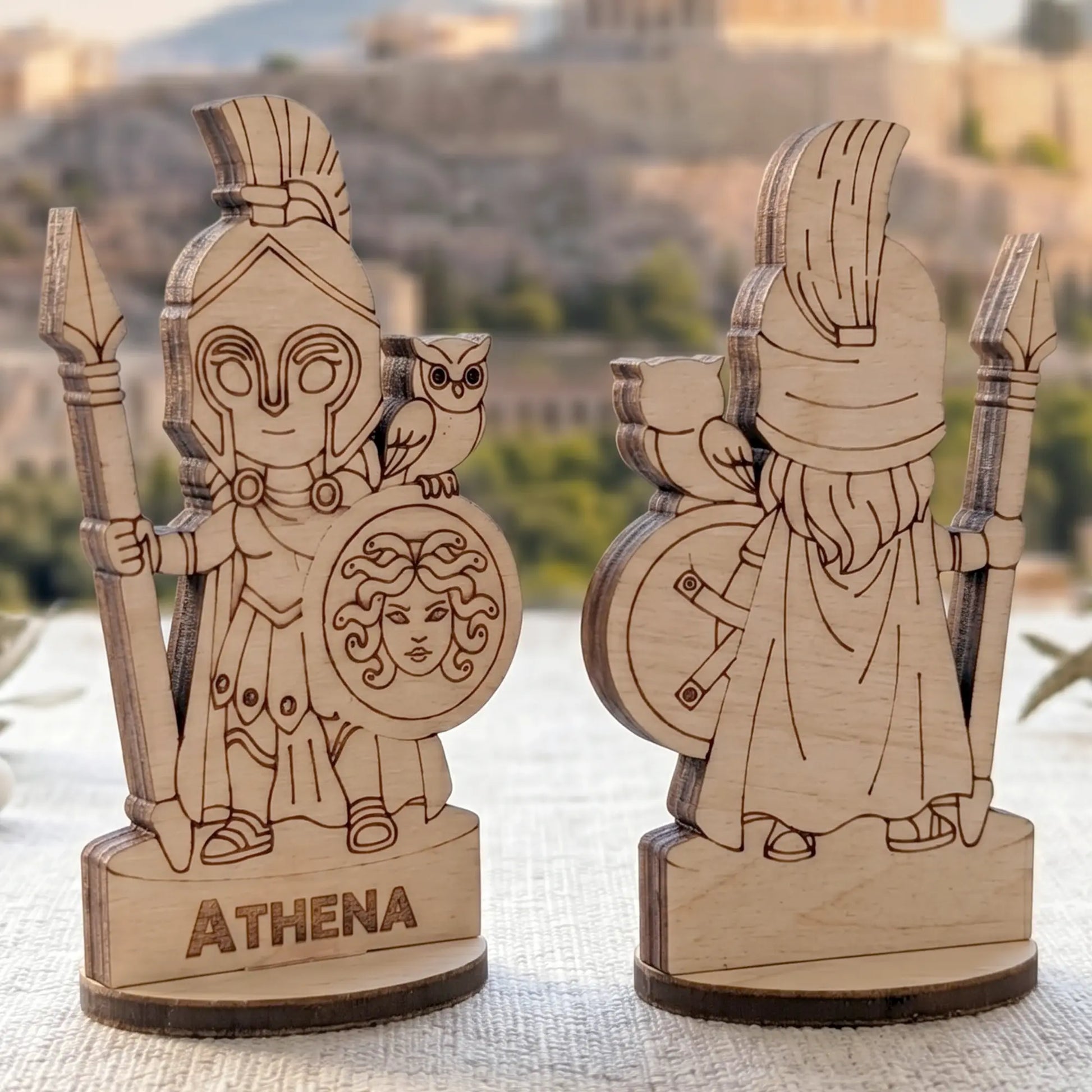 Angled side view of laser cut plywood Athena figurines showing the dark burnt edges and layered texture of the birch wood