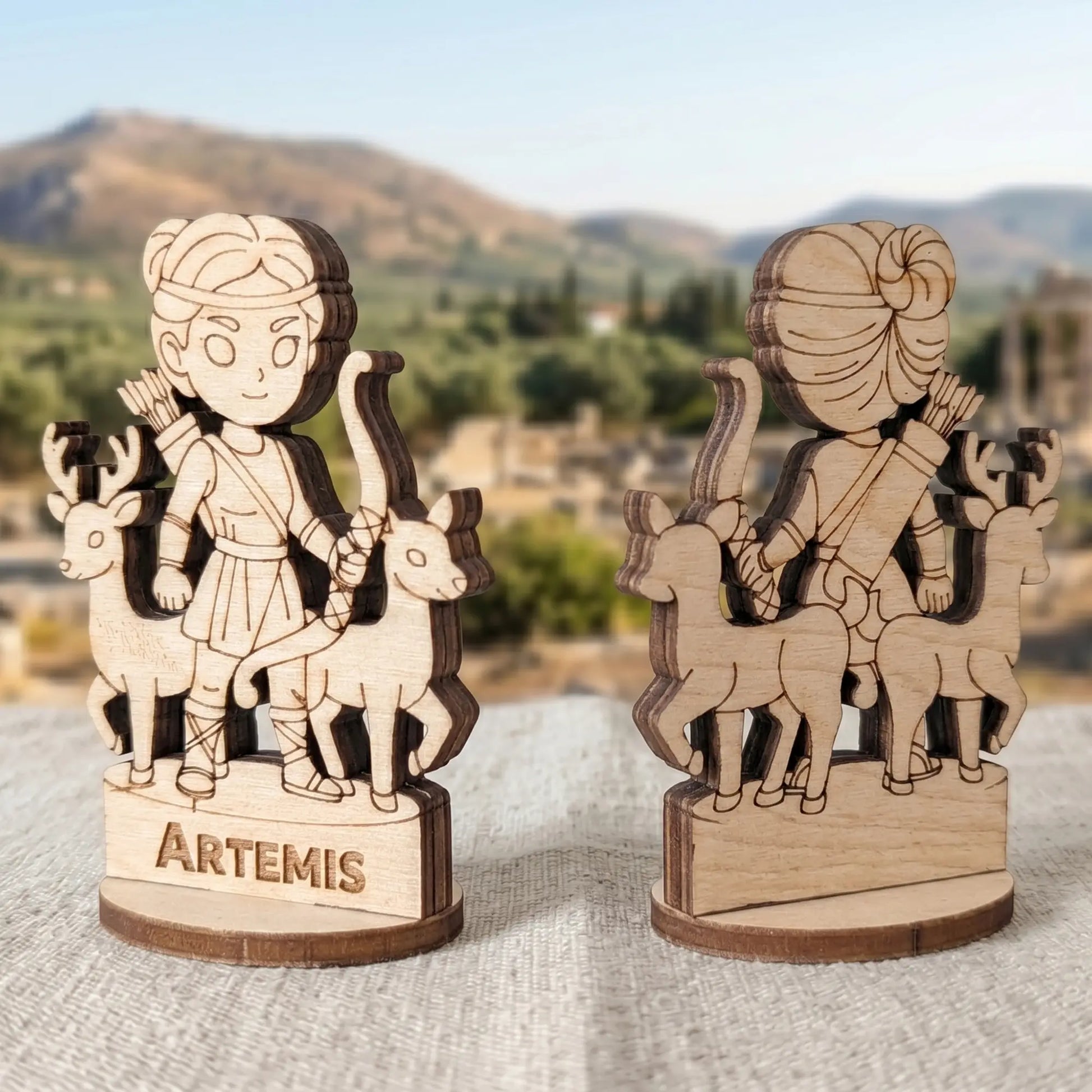 Angled front and back views of a laser cut plywood Artemis figurine, showing dark burnt edges and layered birch wood texture
