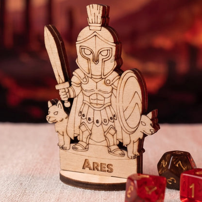 Laser cut plywood Ares miniature on a light surface with sparkly red and brown d20 dice for tabletop RPG scale reference