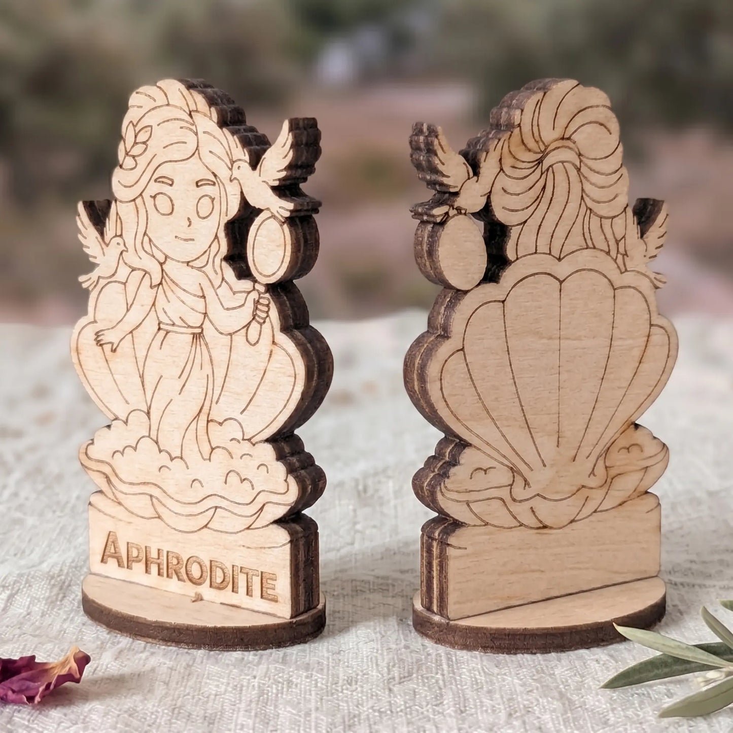 Angled side view of a laser cut plywood Aphrodite figurine showing dark burnt wood edges and detailed layered texture