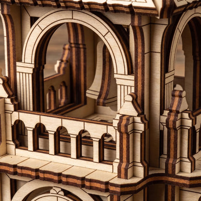 Close-up of the delicate upper balcony arches and a tiny hanging bell inside a layered laser cut plywood tower toy.