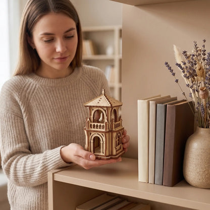 A woman showcasing a miniature fantasy bell house made from laser cut plywood, demonstrating its tabletop home scale.
