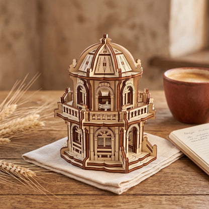 Miniature laser cut plywood dome building on a textile napkin alongside dried wheat ears and a warm coffee cup.