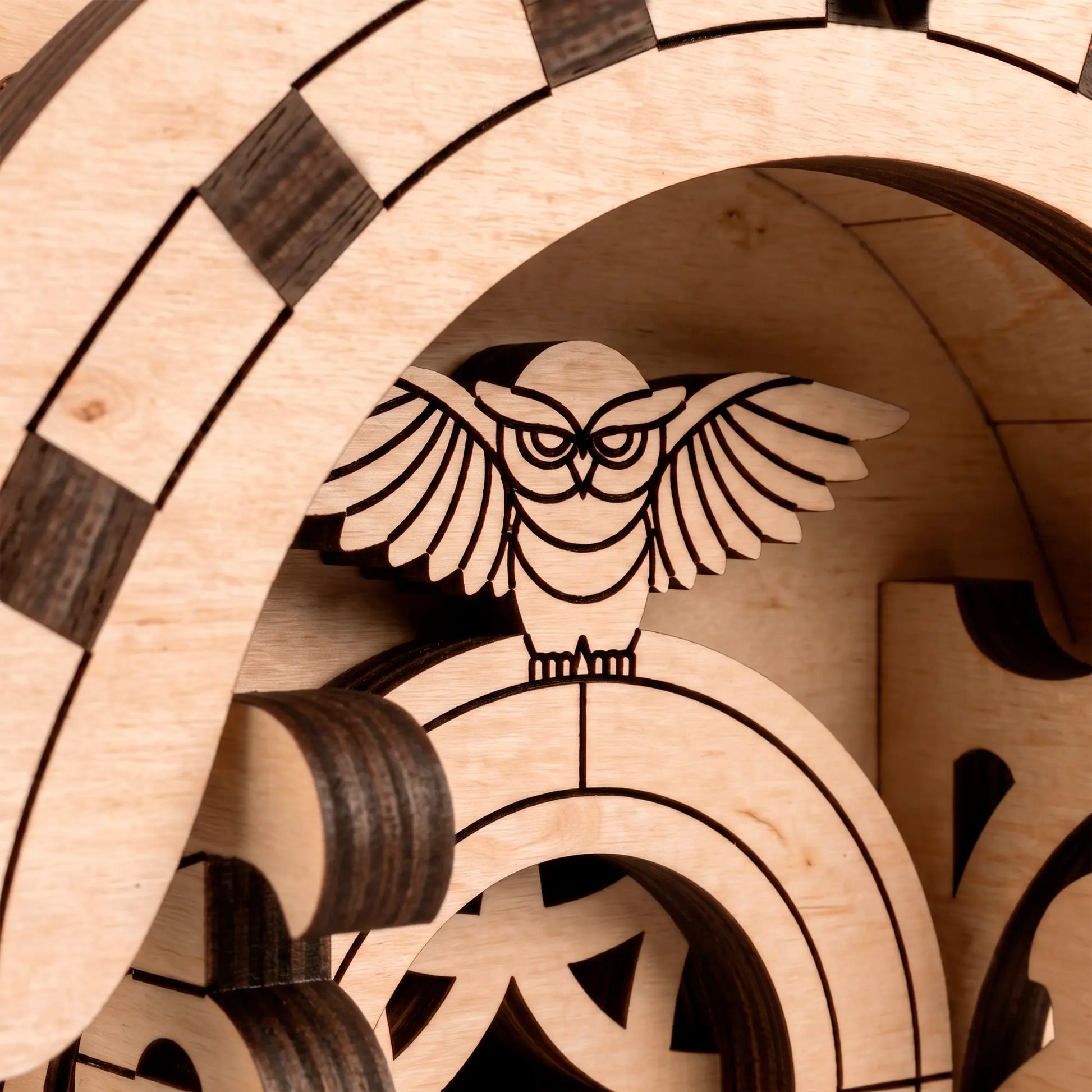 Extreme close-up of the laser-cut wooden owl figure perched on an archway inside the wagon model, showing precise craftsmanship