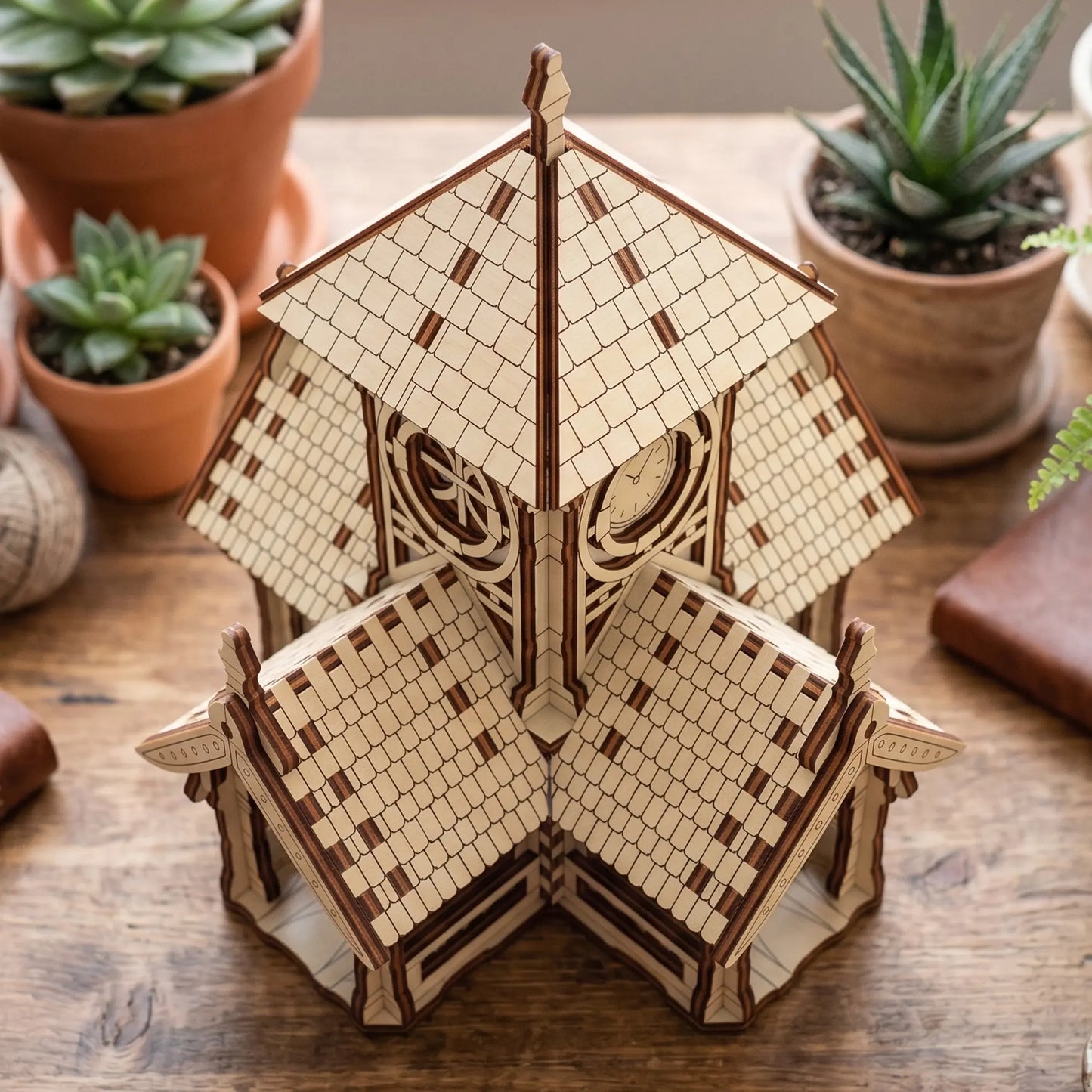 Top-down perspective view of a miniature multi-roofed clock tower house puzzle crafted from laser cut plywood.