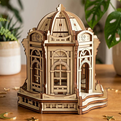 Three-quarter view of an assembled laser cut plywood fairy temple model staged next to a small potted succulent.