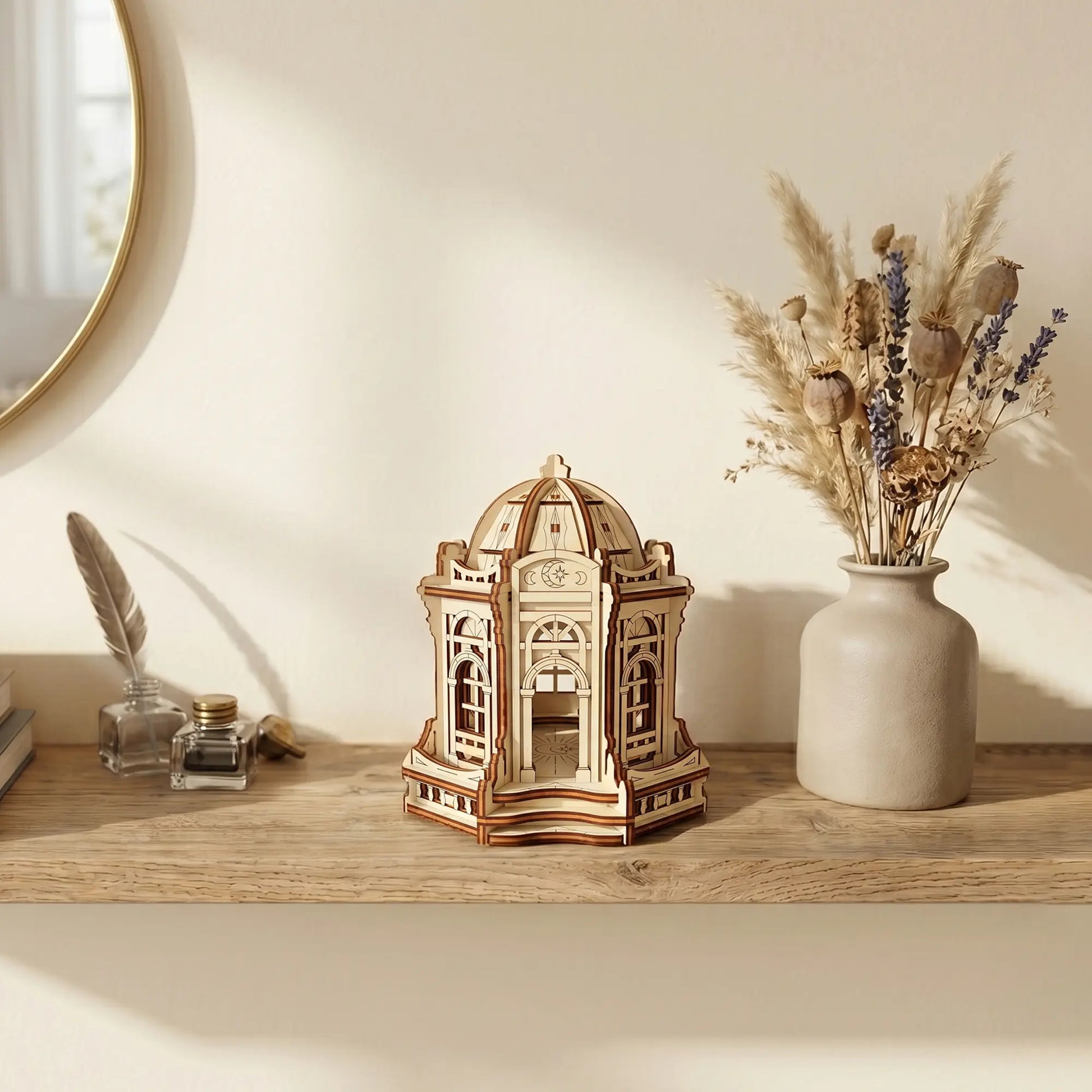 Miniature laser cut plywood moon palace on a desk surrounded by a globe, star maps, and celestial home decor.