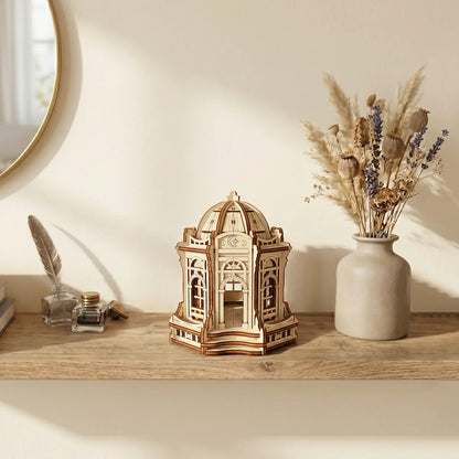 Miniature laser cut plywood moon palace on a desk surrounded by a globe, star maps, and celestial home decor.