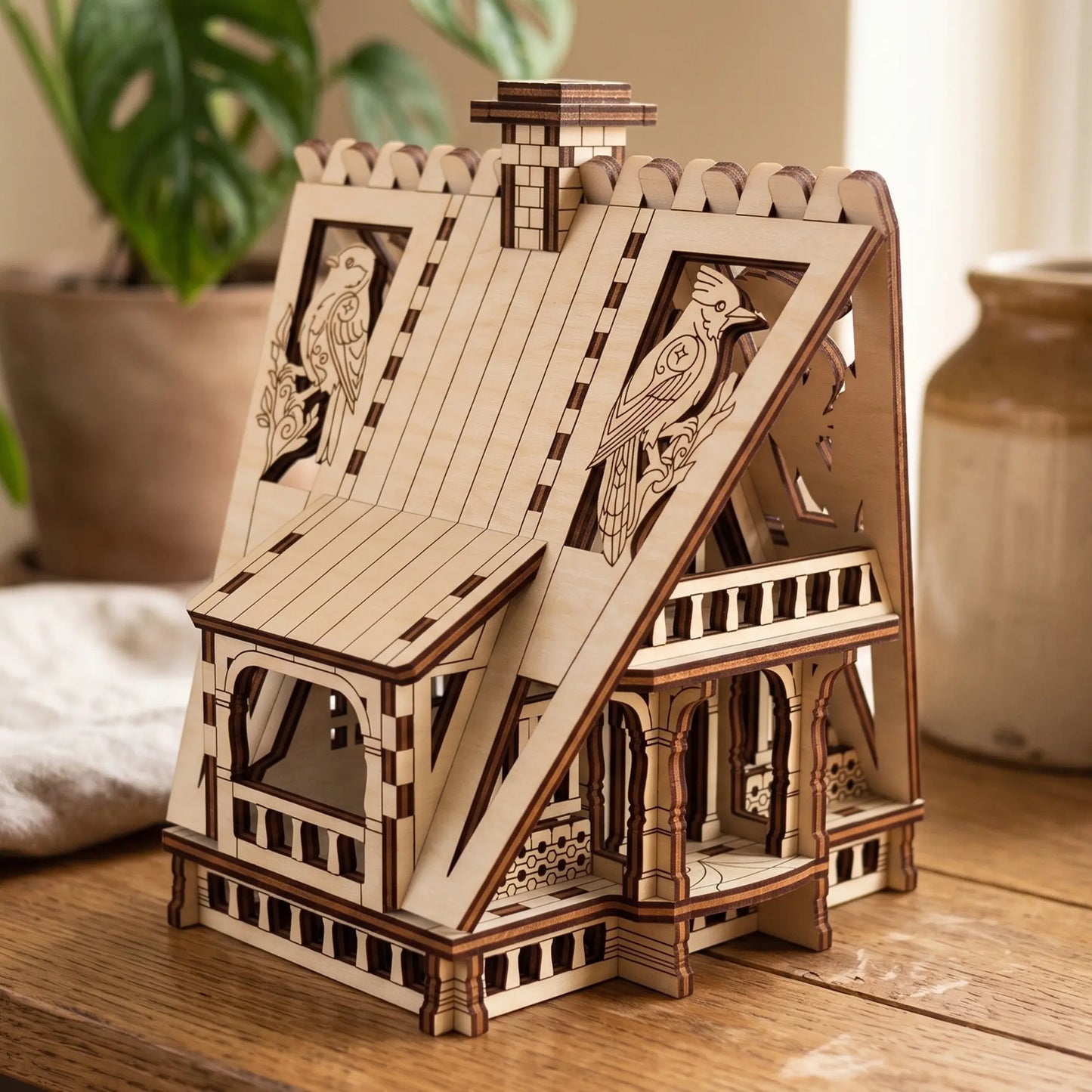 Side angle view of an assembled miniature forest cottage with bird carvings made of premium laser cut plywood.
